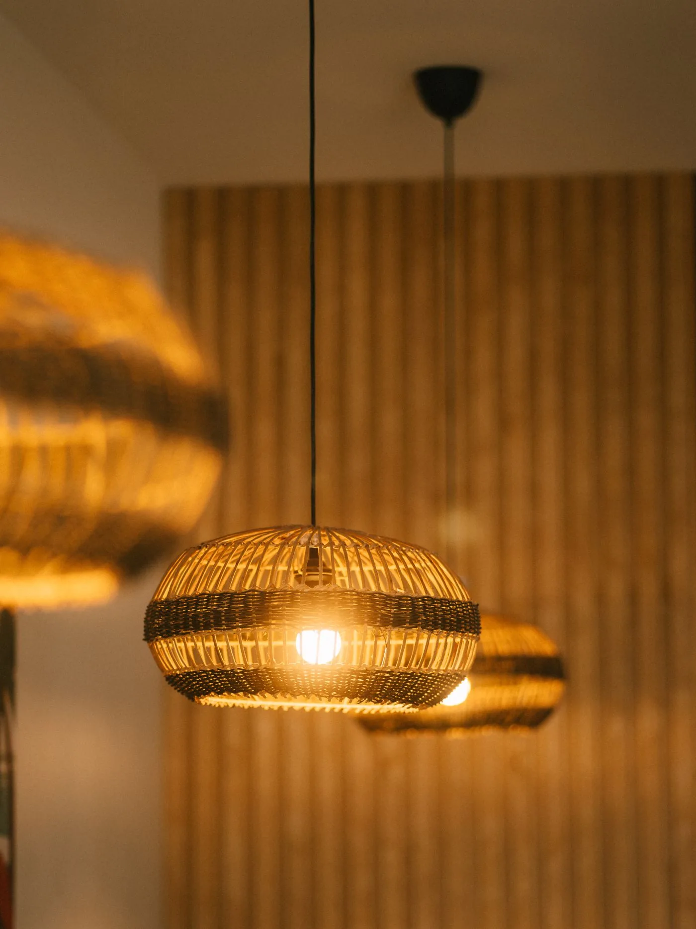 Illuminated woven pendant fixtures casting warm light across a restaurant interior